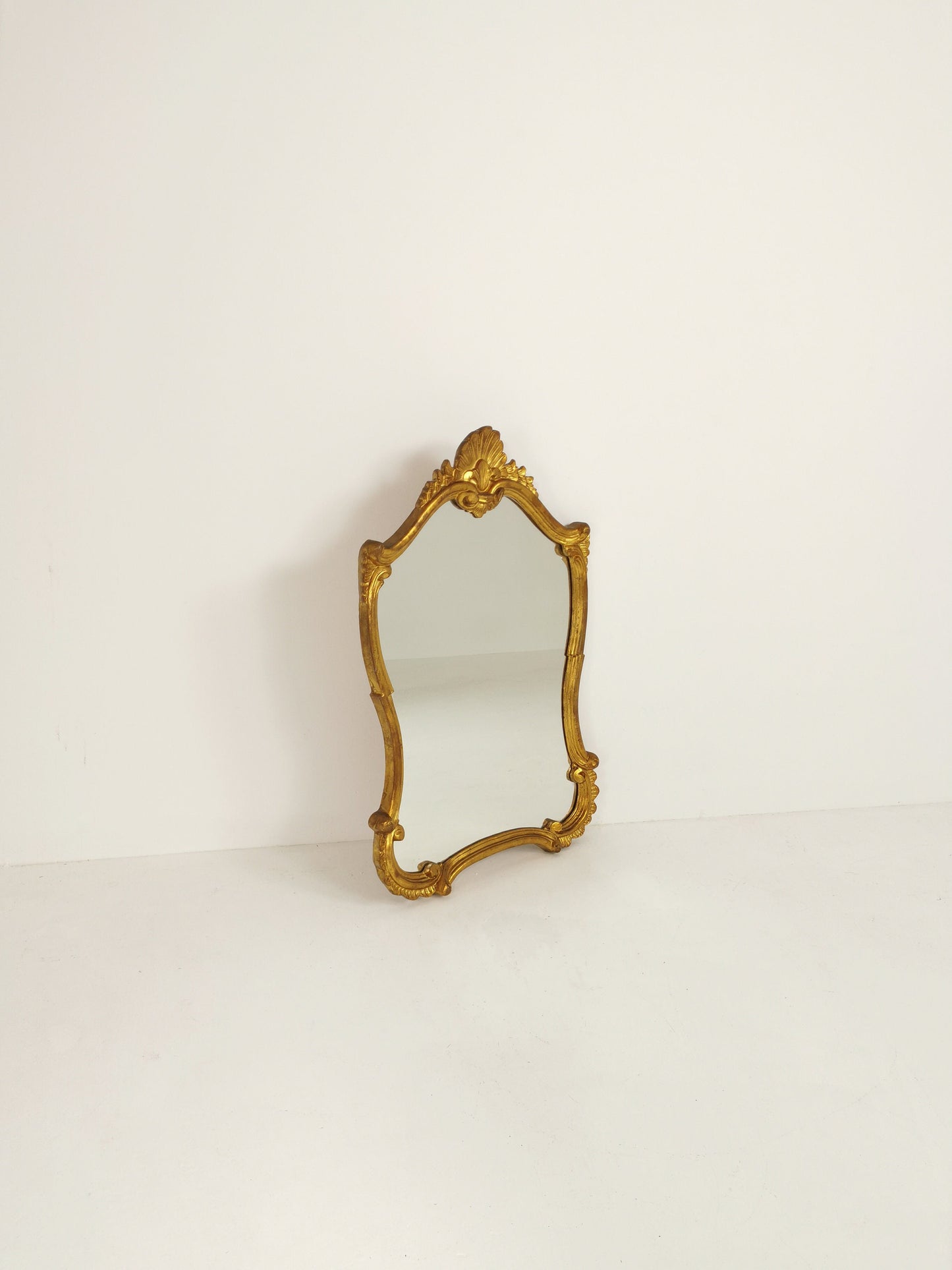 Classic style mirror in gold leaf with shaped frame Italy 1980s.
