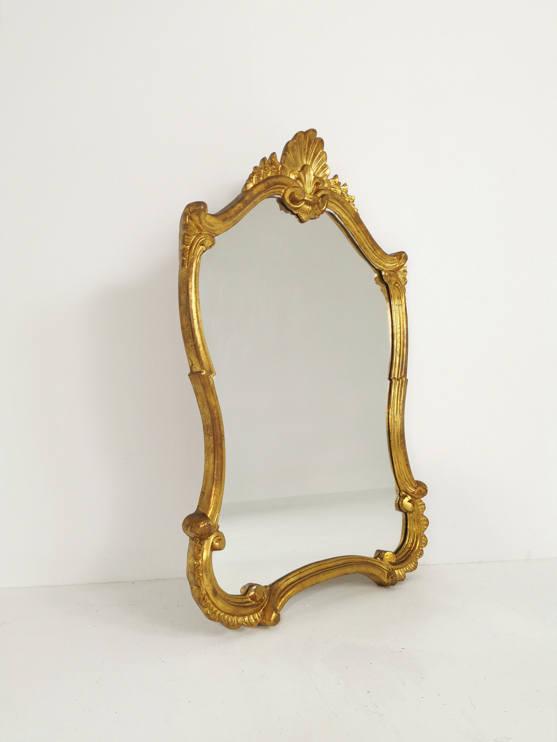 Classic style mirror in gold leaf with shaped frame Italy 1980s.
