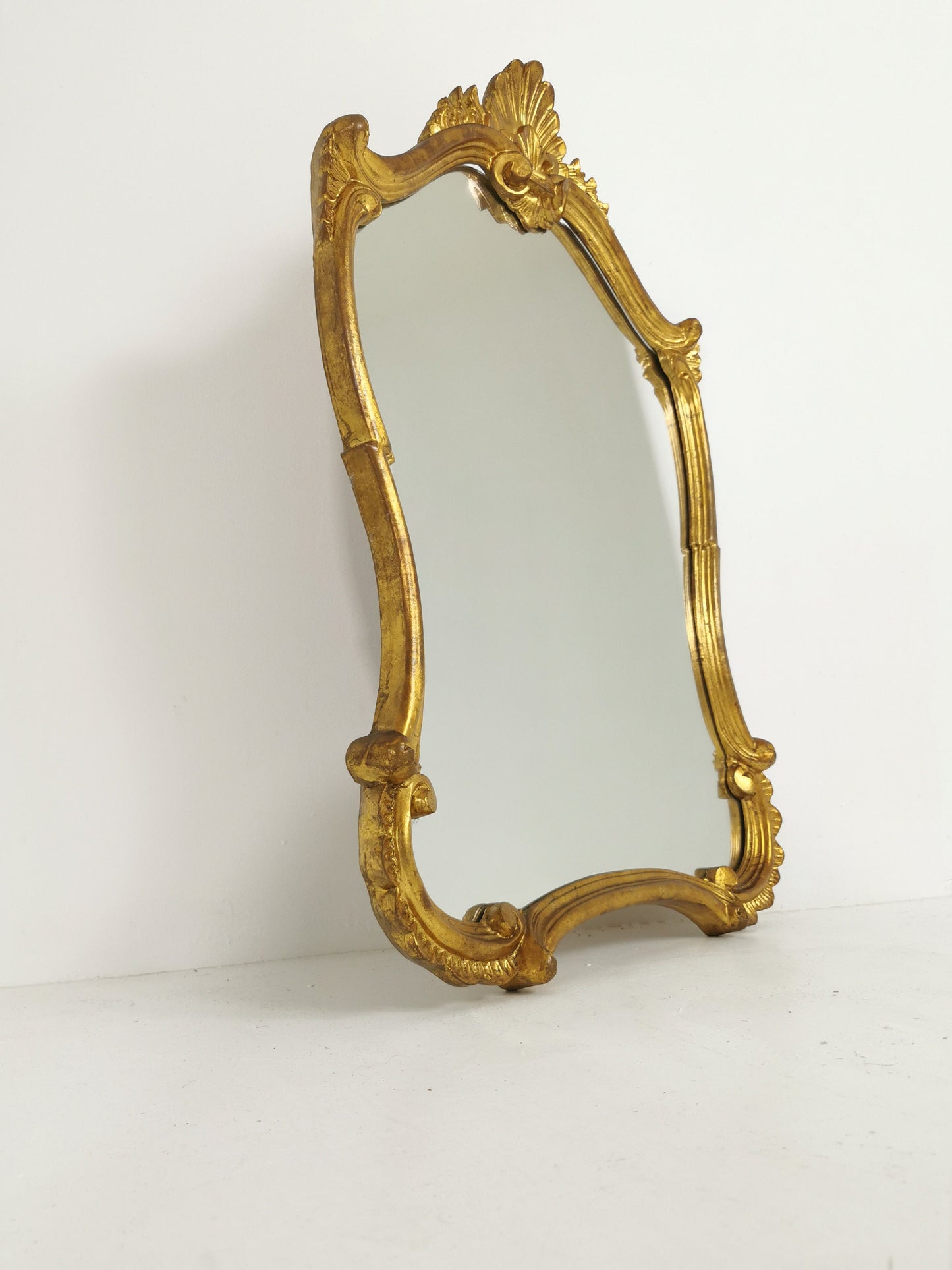 Classic style mirror in gold leaf with shaped frame Italy 1980s.