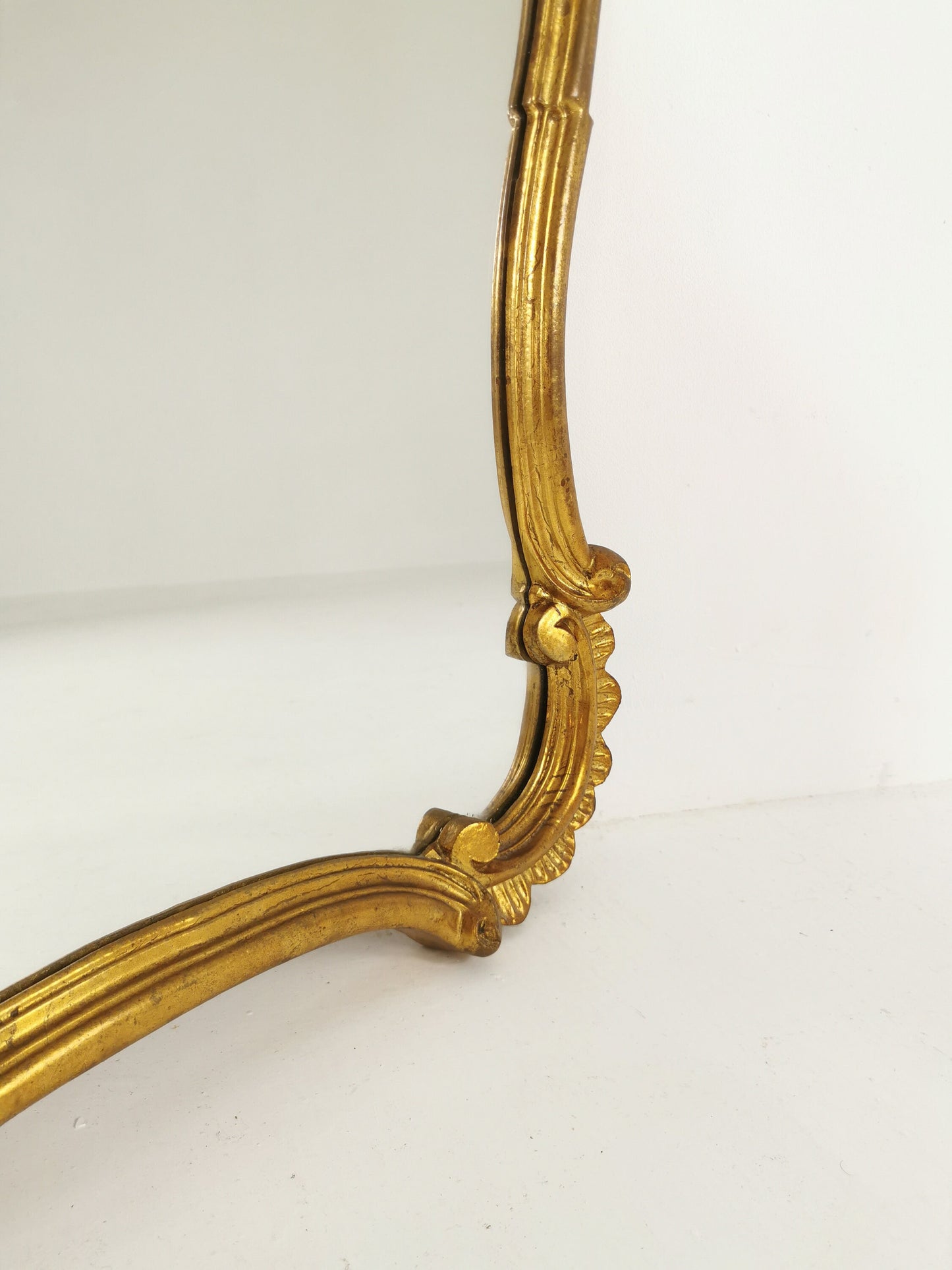 Classic style mirror in gold leaf with shaped frame Italy 1980s.