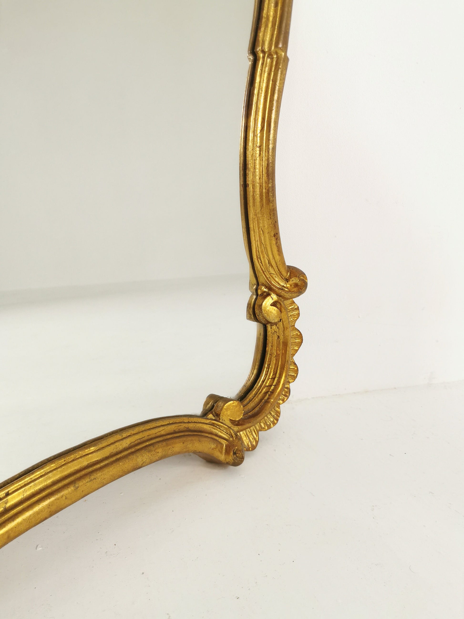 Classic style mirror in gold leaf with shaped frame Italy 1980s.