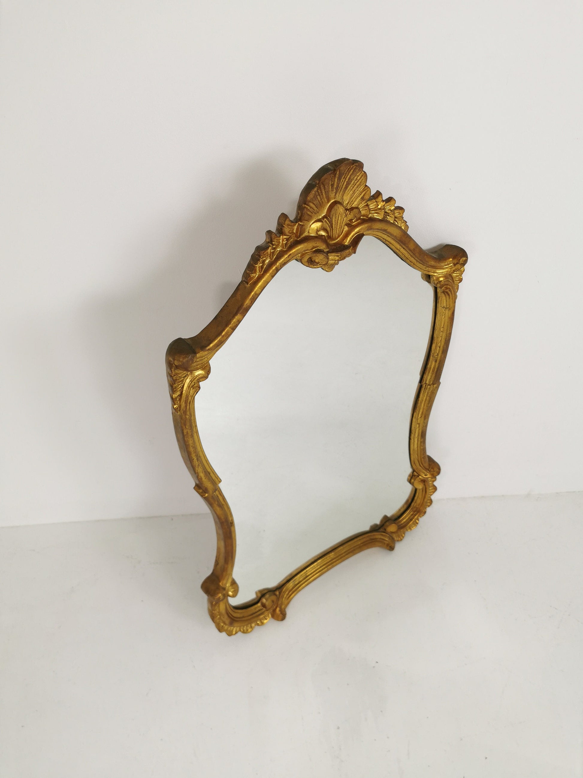 Classic style mirror in gold leaf with shaped frame Italy 1980s.