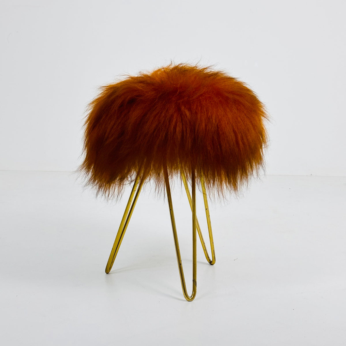 Beautiful midcentury orange flokati stool with goat hair cover and tripod hairpin feet. 1950s