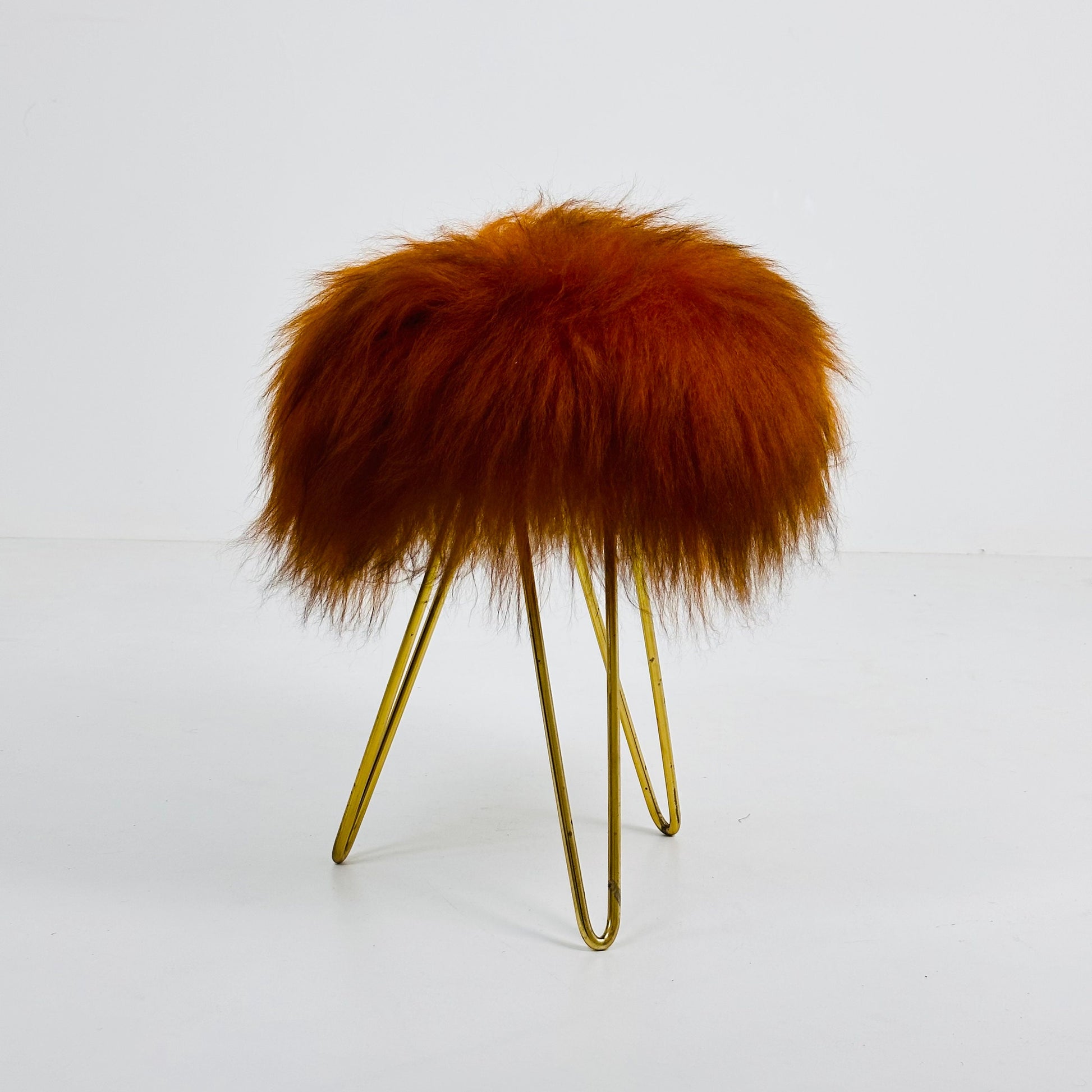 Beautiful midcentury orange flokati stool with goat hair cover and tripod hairpin feet. 1950s