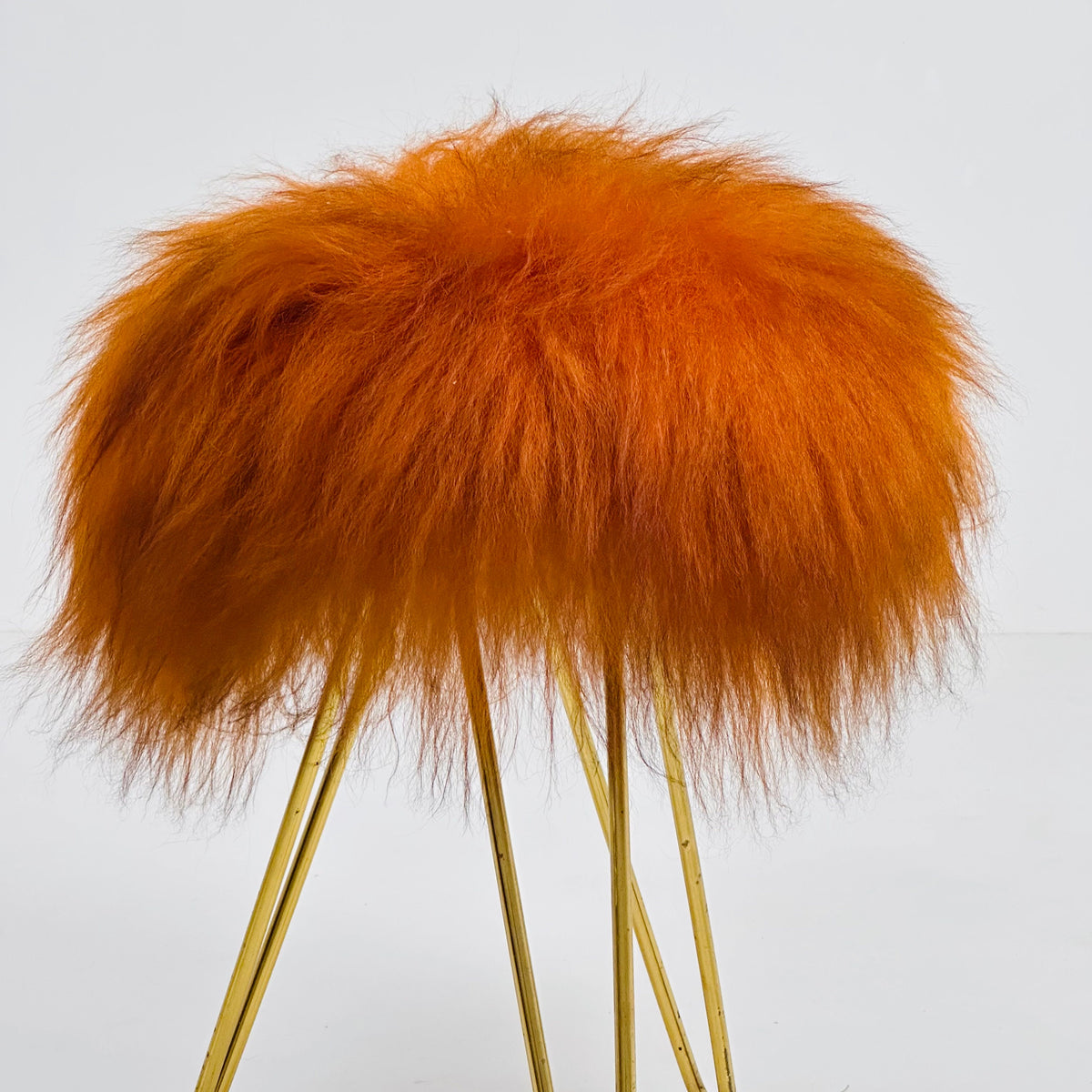 Beautiful midcentury orange flokati stool with goat hair cover and tripod hairpin feet. 1950s