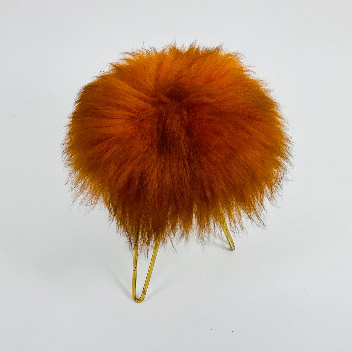 Beautiful midcentury orange flokati stool with goat hair cover and tripod hairpin feet. 1950s